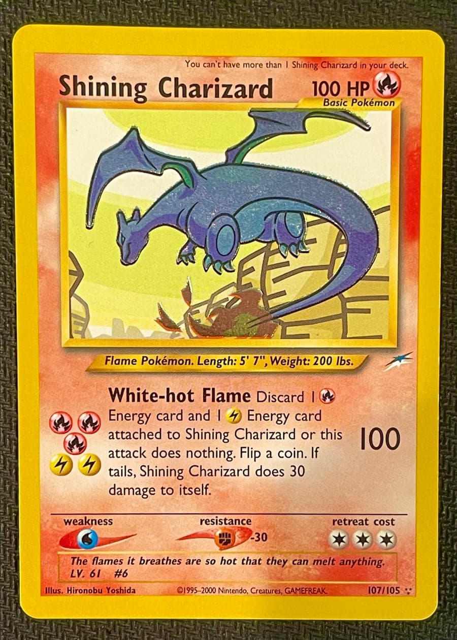 Reference photo: the front of a Shining Charizard card, shot flat on dark fabric with even lighting and all four corners visible